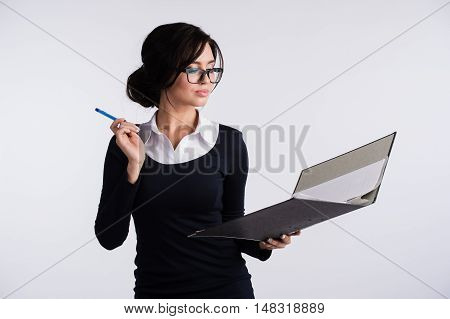 Young Caucasian woman wearing a dark blue dresst and and a white shirt, holding a ring binder folder and pen. Isolated on light background