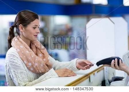 Customer making payment through payment terminal in pharmacy