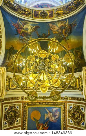 SAINT PETERSBURG RUSSIA - APRIL 25 2015: The chandelier and painted ceiling of St Isaac's Cathedral depicting the scenes from Holy Bible on April 25 in Saint Petersburg.
