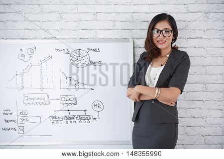 Confident smling business lady standing at whiteboard with charts
