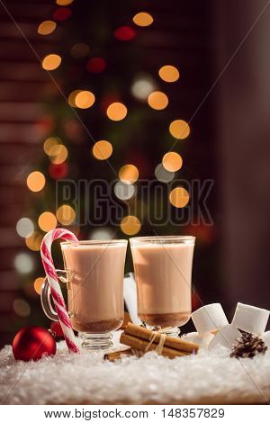 Composite image of hot chocolates against Christmas tree background