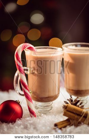 Extreme close up view of composite image of hot chocolates against Christmas tree background
