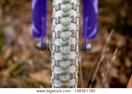 Close up of a bicycle tire on a child sized bike. Just the center tred is in focus and the tire has rocks stuck in the grooves.
