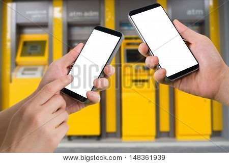human hand hold and touch smartphone tablet cell phone with blank screen virtual internet banking on blurry cash machines background transfer money concept.