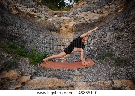 Man doing yoga outdoors. Parshvakonasana. Side view