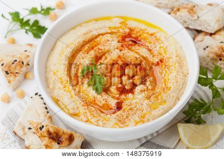 Hummus or houmous appetizer made of mashed chickpeas with tahini, lemon, garlic, olive oil, parsley and paprika.