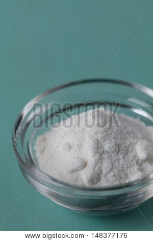 Baking soda, sodium bicarbonate in glass bowl on wooden table.