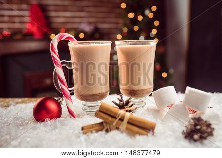 close up view of composite image of hot chocolates against Christmas tree background