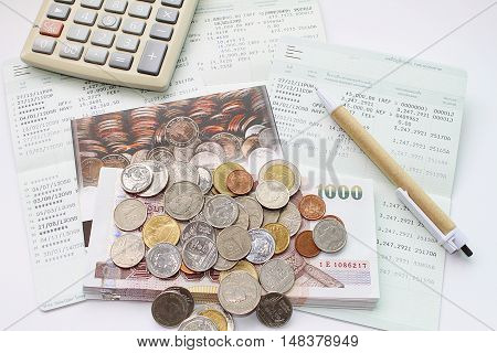 Concept of savings : Coins, money, calculator and pen on savings account passbook
