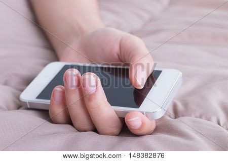 Woman hand with mobile phone sleeping on bed.