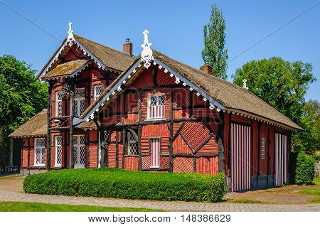 Typical old house with a thatched roof and walls covered with thin brown red painted tree trunks. The building built in 1875 is a Dutch national monument.