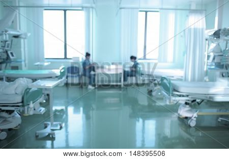 Two nurses are on duty in ICU defocused background.