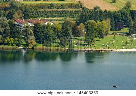 Coast of Levico Lake (Lago di Levico) with tourists swimmers and people sunbathers. Levico Terme Trentino Alto Adige Italy Europe