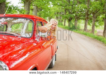 Woman hanging out of retro cars window