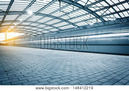 Modern high-speed train departs from the station at sunset.