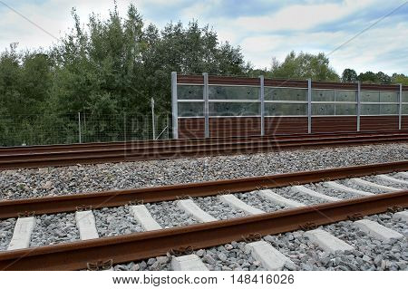 Railway with noise damping wall. Rail Baltica railroad protective fences.