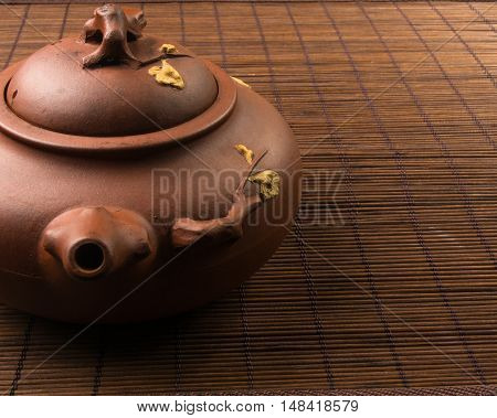 brown Chinese teapot of Yixing clay with traditional ornament on bamboo Mat