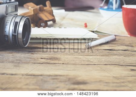 Planing travel background concept. Old film camara and stuffs on wooden table. Vintage tone Retro filter effect Soft focus Low light.(selective focus)