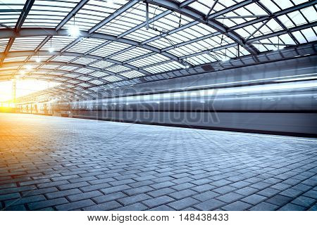 Modern high-speed train departs from the station at sunset.