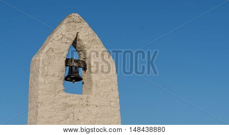 Small bell tower with a bell of a Welsh country chapel, against a deep blue sky