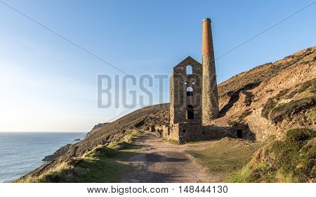 Derelict Cornish tin mine, on the cliff edge, against a blue sky