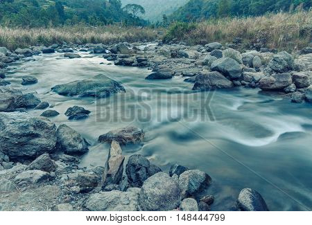 Beautiful Reshi River water flowing through stones and rocks at dawn Sikkim India. Blue tinted image. Reshi is one of the most famous rivers of Sikkim flowing through the state and serving water to many local people.