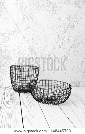 Vintage wire baskets on white wooden rustic floor industrial wicker storage bins
