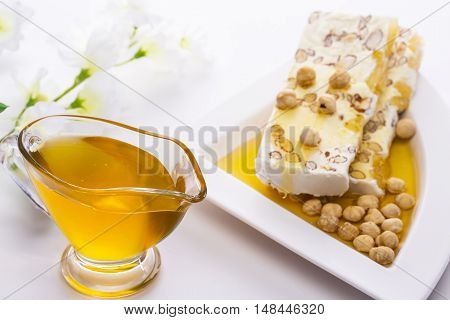 Honey in a saucepan and poured honey candy and nuts on a white plate