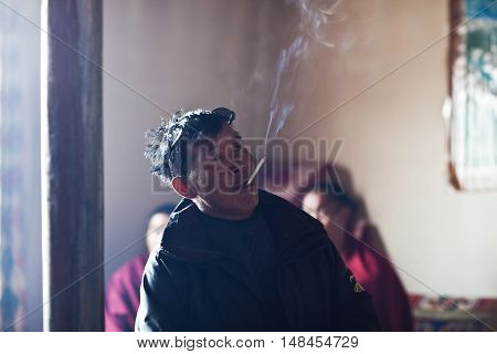 DARCHEN, CHINA - MAY 4, 2013: Tibetan man smoking in dinner room of monastery guesthouse in Darchen village, Tibet Autonomus Region of China