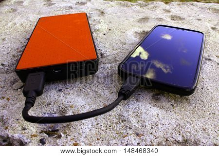 Brown powerbank and smartphone on concrete background angle view