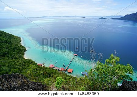 View from the peak of Bohey Dulang Island,Sabah,Borneo.Mirror smooth ocean surrounded by mountains.The bright blue water and rocky shore in the tropical island of Semporna,Sabah,Borneo.