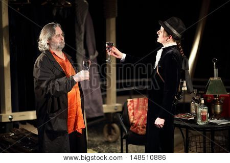 RUSSIA, MOSCOW - APR 15, 2015: Two actors are drinking alcohol beverages and playing his characters for performance (Kosmos) at drama theatre Modern.
