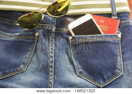 Passort and mobile phone in the pocket of blue jeans and sunglasses a man goes on a big journey