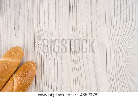 Bun with sesame seeds on old white wooden table. Top view.