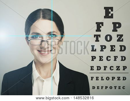 Beautiful woman with laser hologram and test vision table over dark background