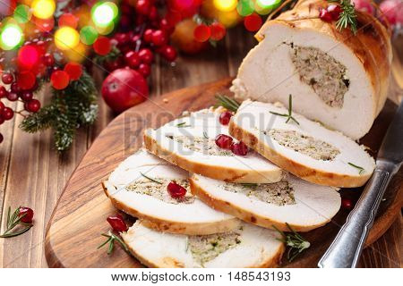 Stuffed turkey breast with pomegranate and rosemary on cutting board.