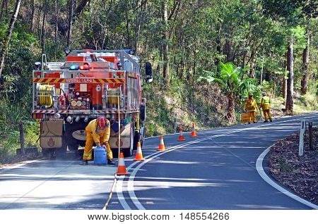 September 11, 2016. Waterfall fire brigade manage an oil spill from broken down tour bus engine in Royal National Park, Sydney, Australia. Road dangerous, slippery and closed for chemical clean up