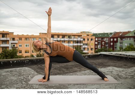 Beautiful woman practicing yoga on the roof,Trikonasana Bikram/Bikram triangle right
