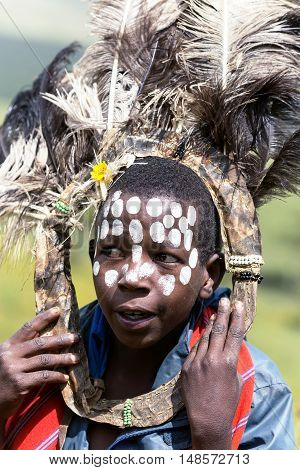 AFRICA, KENYA, MAY, 08, 2016 - African children with ostrich feather headdress  and painted markings of face at Masai Mara National Park, Kenya, Africa