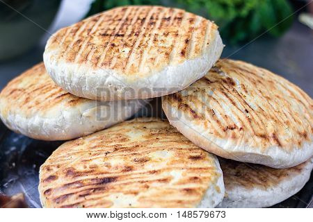 Georgian traditional dish khachapuri, pastry flat cake cheese-filled bread fried on the grill, BBQ. Fresh hot tasty street food in the market. Cooking food. Preparation dish of Middle Eastern cuisine.