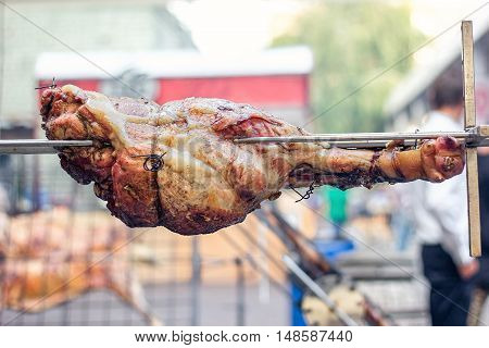 Appetizing grilled pork on the spit. Roasted leg of porkon traditional barbecue. Prepared of a ram pig baked pork meat Street food Whole Pork knuckle roasting on the grill over charcoal.