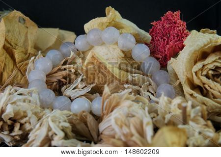 agate bracelet lying on a yellow rose, black background