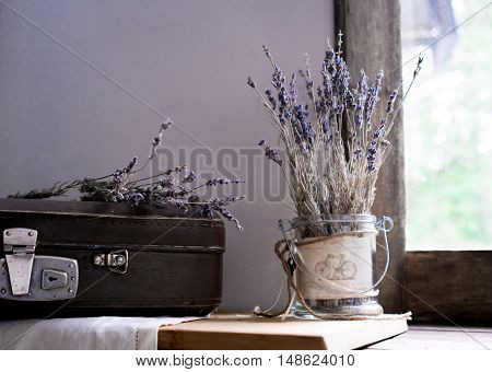 still life. vintage. old suitcase and sprigs of lavender on the background of old windows to the garden.