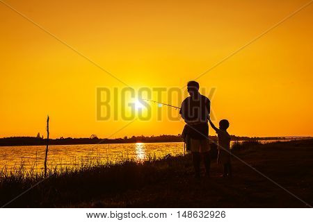 father and son fishing in the river sunset backgrond