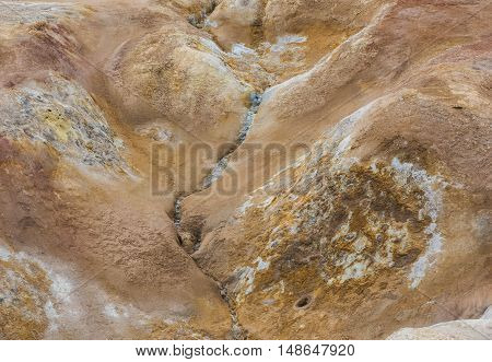 Geothermal landscape Krafla on Iceland with red dirt a hot water stream and steam.
