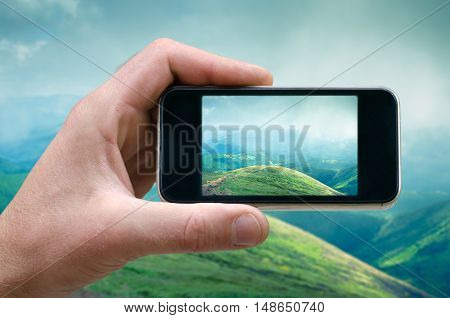 phone in hand man photographing the landscape photos from your phone, Selfie, photographing on the phone, the man photographs the mountain landscape on the phone smartphone side view. carpathians