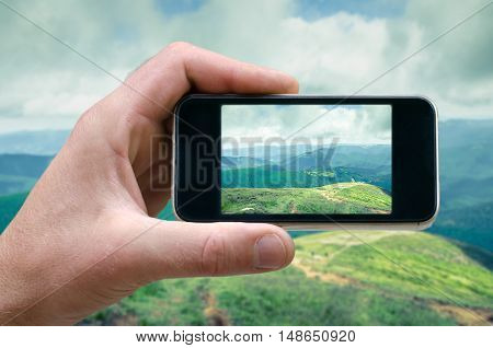 phone in hand man photographing the landscape photos from your phone, Selfie, photographing on the phone, the man photographs the mountain landscape on the phone smartphone side view. carpathians