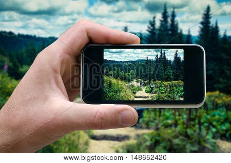 phone in hand man photographing the landscape photos from your phone, Selfie, photographing on the phone, the man photographs the mountain landscape on the phone smartphone side view. carpathians