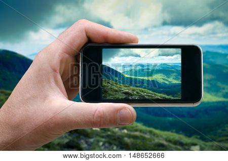 phone in hand man photographing the landscape photos from your phone, Selfie, photographing on the phone, the man photographs the mountain landscape on the phone smartphone side view. carpathians