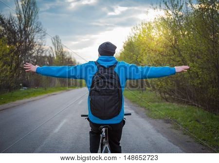 man riding a bike on the highway, arms outstretched. sport